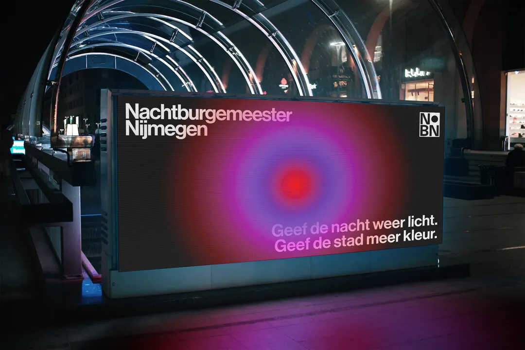 A billboard at night: Geef de nacht weer licht. Geef de stad meer kleur.